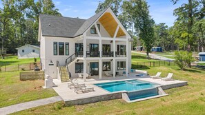 A two-story house with a balcony, a swimming pool, and a fenced yard.