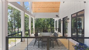Eine überdachte Terrasse im Freien mit Esstisch und Stühlen, umgeben von Glastüren und Fenstern.