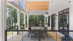 Eine überdachte Terrasse im Freien mit Esstisch und Stühlen, umgeben von Glastüren und Fenstern.