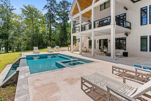 Une maison à deux étages dotée d’une piscine, d’un espace salon extérieur et d’un patio couvert.