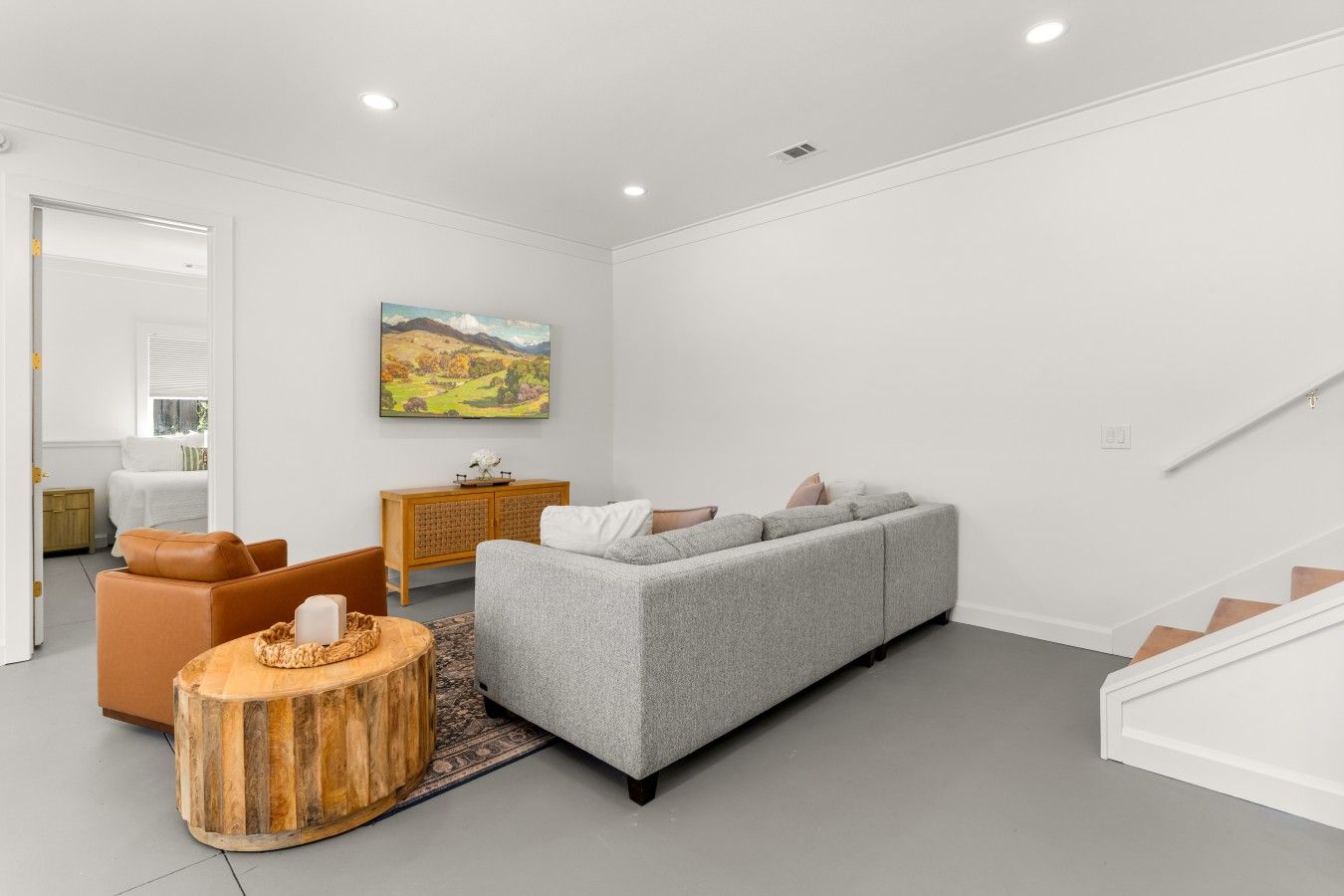 A modern living room with a grey sofa, a wooden side table, and a painting on the wall.