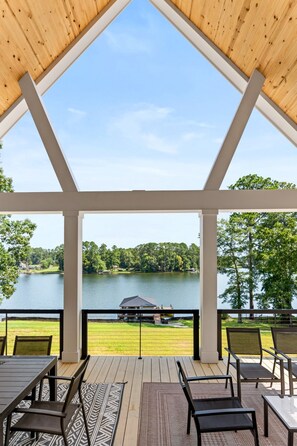 A covered outdoor seating area with a view of a lake and surrounding greenery.