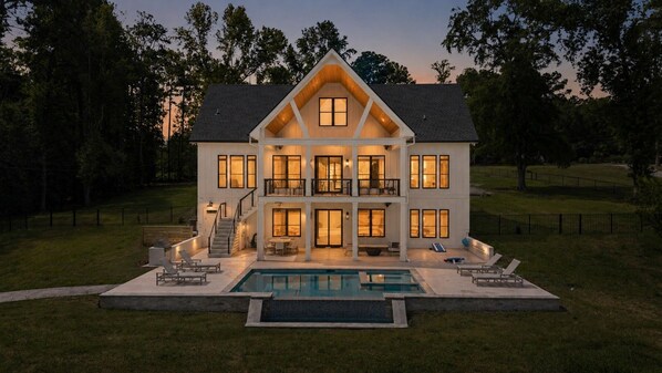 A two-story house with a swimming pool in front.