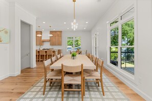 A spacious dining area with a long table, multiple chairs, and a chandelier. - Lake Sinclair Dream Home w/ Everything|Pool|HotTub (Milledgeville)