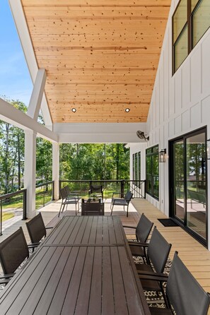 An outdoor patio with a wooden ceiling, a table with chairs, and a view of trees. - Lake Sinclair Dream Home w/ Everything|Pool|HotTub (Milledgeville)