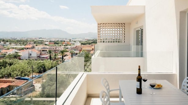 A balcony with a table, chairs, a bottle of wine, and glasses. - Almar Suites Daimús (Daimús)
