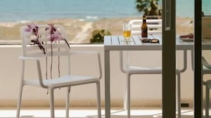 A balcony with a table and chairs, overlooking a beach and ocean. - Almar Suites Daimús (Daimús)
