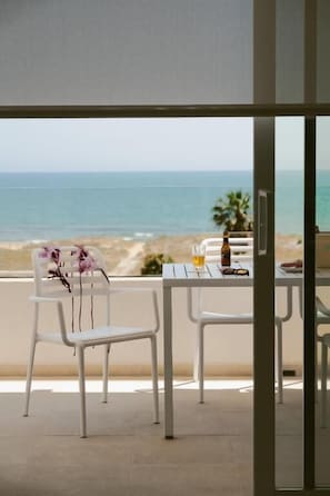 Ein Balkon mit Tisch und Stühlen, mit Blick auf einen Strand und das Meer.