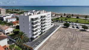 A multi-story building with a parking lot in front, adjacent to a sandy beach and the sea. - Almar Suites Daimús (Daimús)