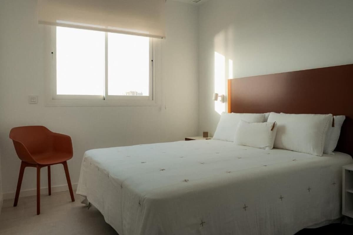 Ein Schlafzimmer mit Bett, Stuhl, Nachttisch und Fenster.