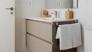 A bathroom with a white sink, mirror, and towel hanging on the wall. - Almar Suites Daimús (Daimús)