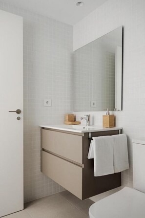 Ein Badezimmer mit einem weißen Waschbecken, einem Spiegel und einem an der Wand hängenden Handtuch.