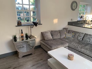 Ein modernes Wohnzimmer mit einem grauen Sofa, einem weißen Couchtisch und einer Vitrine mit dekorativen Gegenständen.
