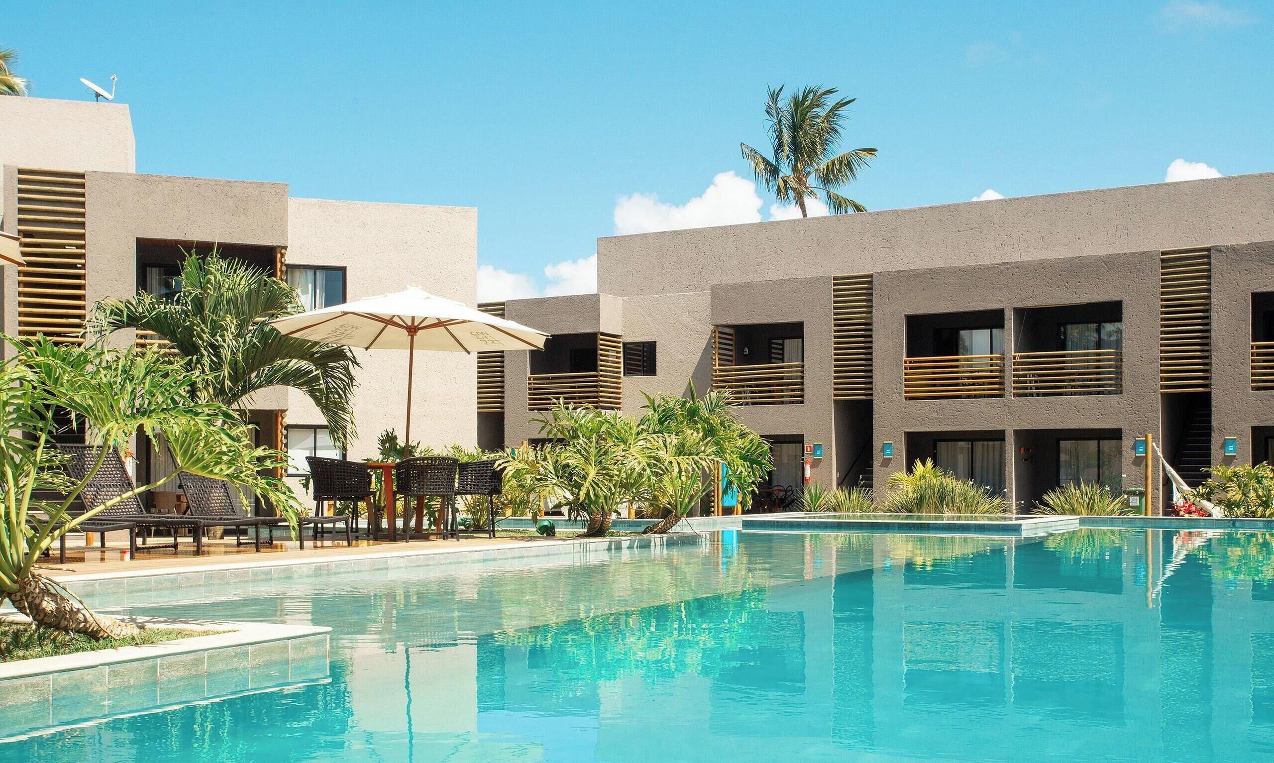 Um hotel com piscina, área de estar externa e palmeiras.