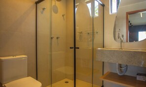 Une salle de bain avec une douche à parois de verre, des toilettes et un lavabo avec un miroir au-dessus.