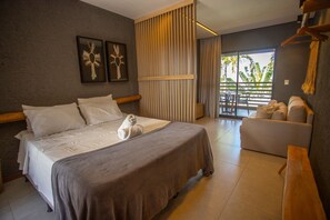 A hotel room with a bed, a sofa, and a view of palm trees through the window. - Studio With Balcony Villas Manatee Patacho by MME (Porto de Pedras)