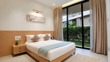 A modern bedroom with a large bed, a nightstand, a wall-mounted light, and a view of a building and greenery outside.
