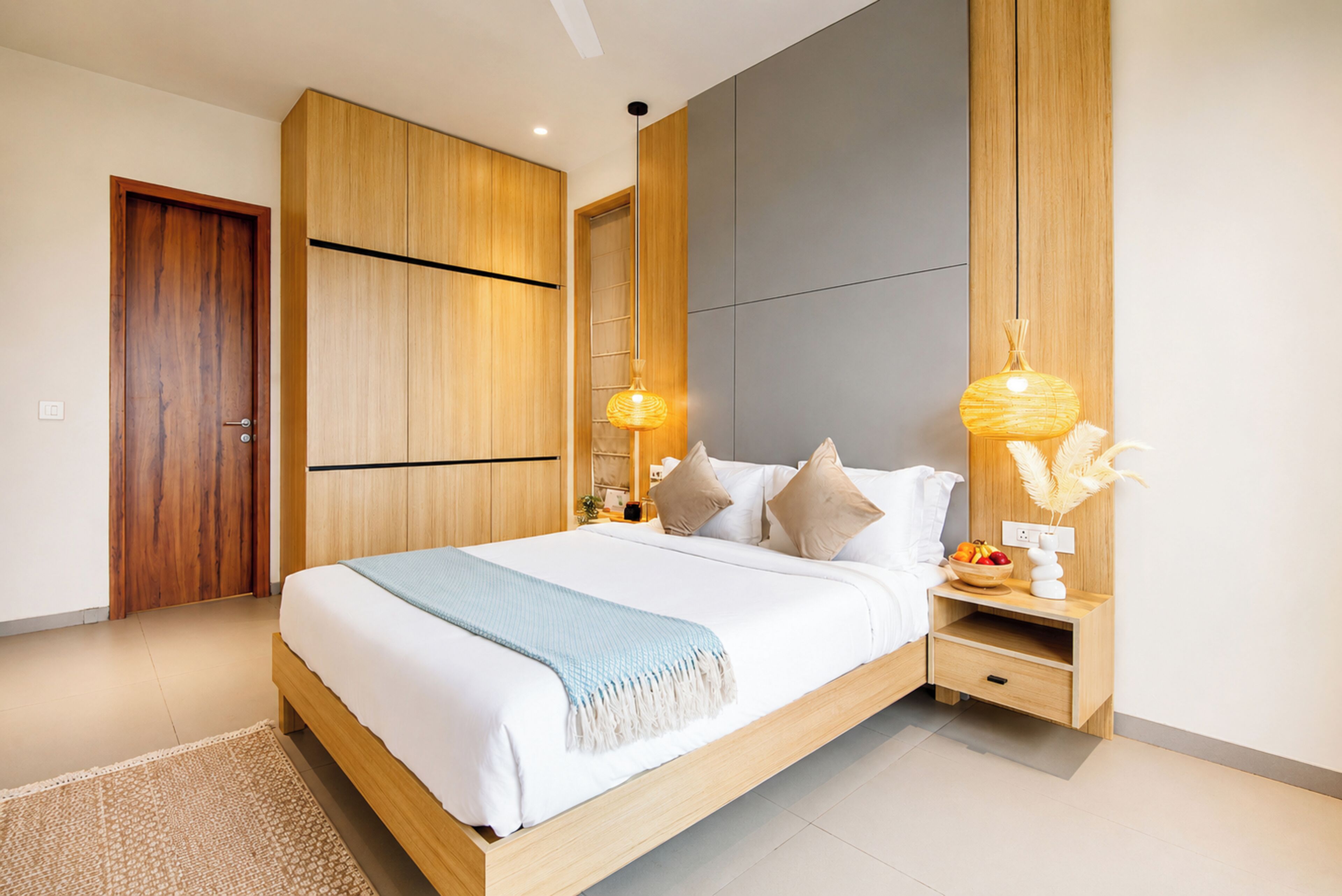 A modern bedroom with a wooden bed frame, a nightstand, and a bedside table with a lamp.