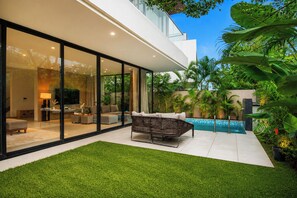 Una casa moderna con fachada de vidrio, piscina y césped cuidado.