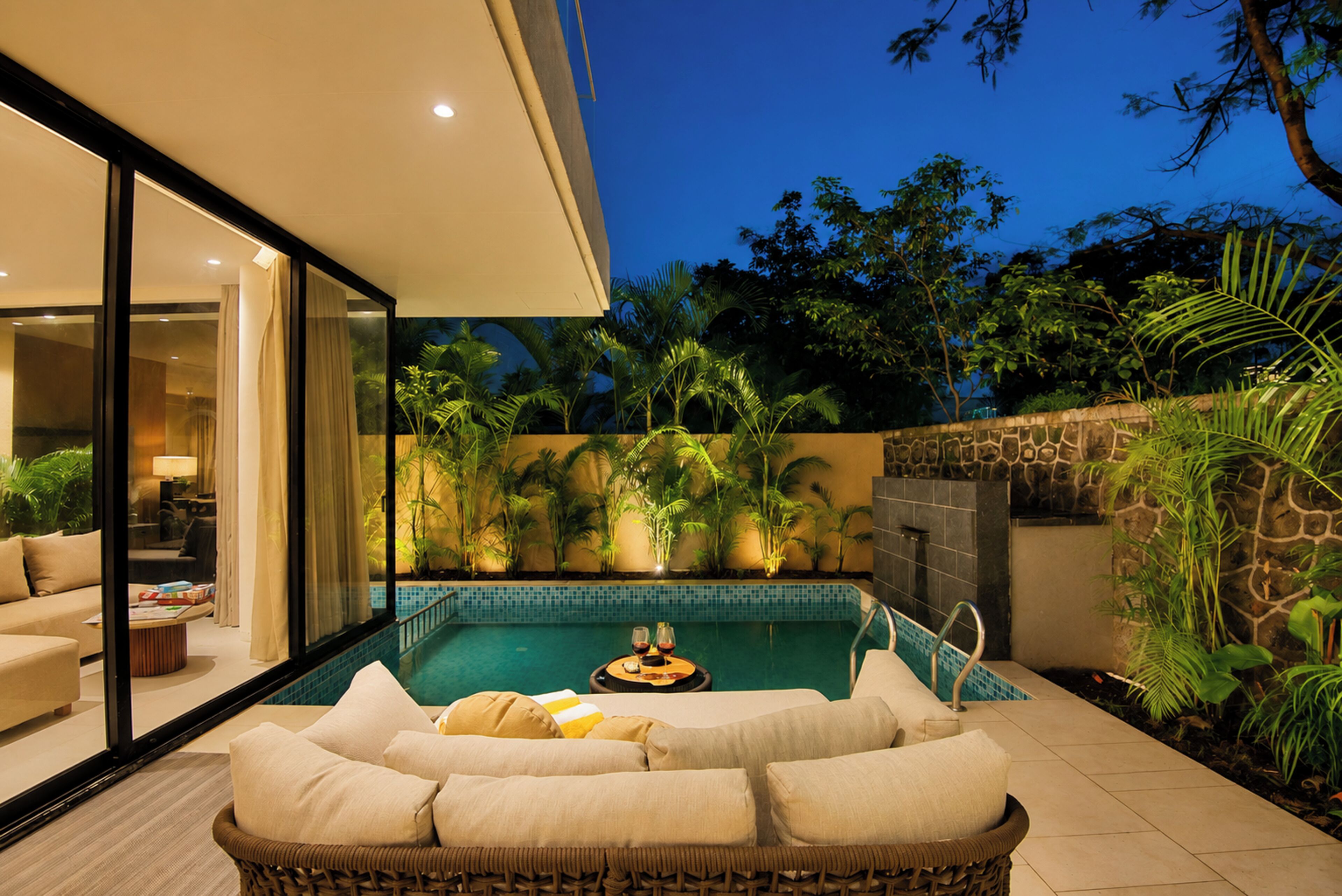A modern outdoor living area with a pool, comfortable seating, and lush greenery.