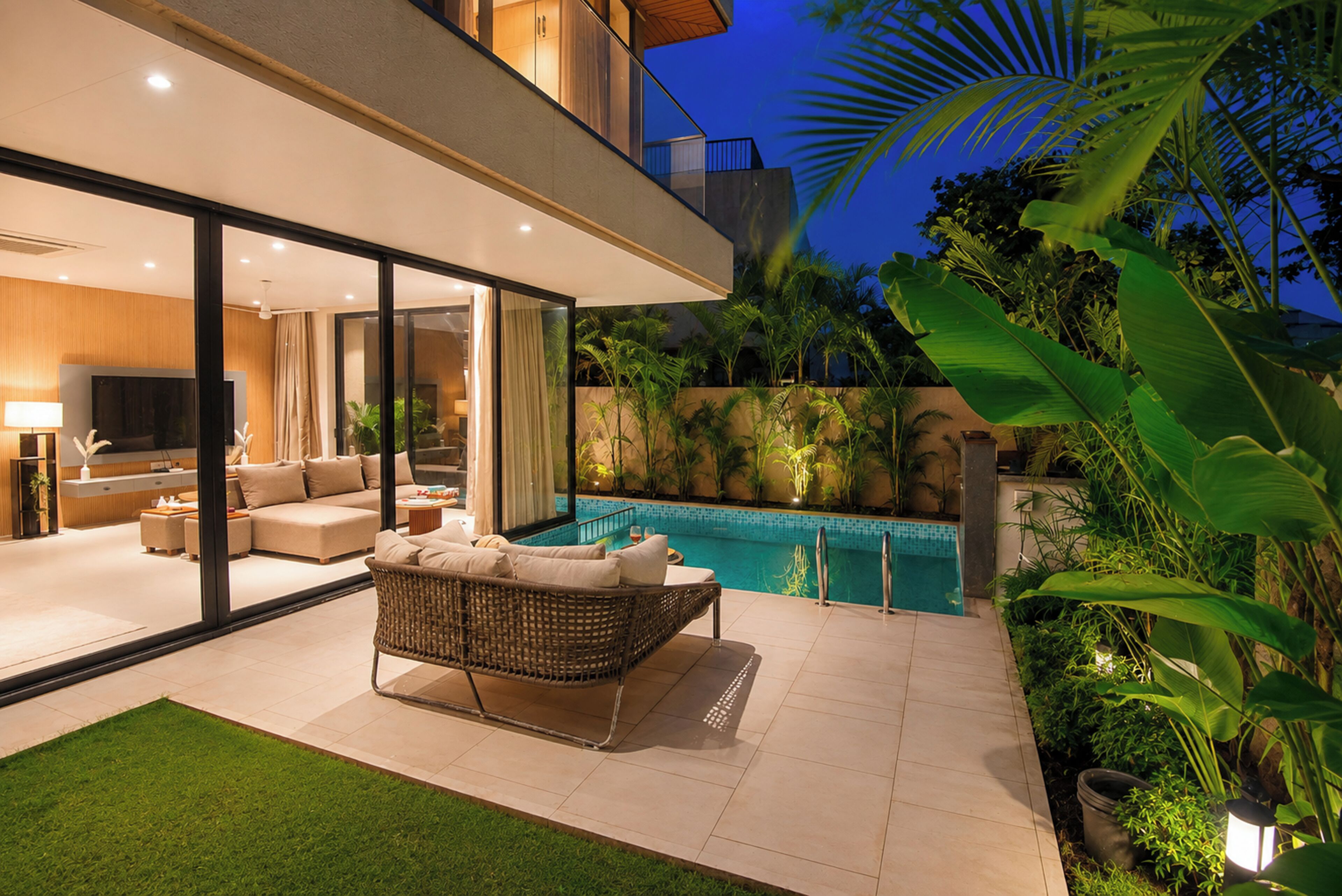 A modern outdoor living area with a pool, a sofa, and a dining table.