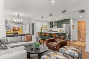 A modern living room with a sofa, armchairs, a coffee table, and artwork on the walls. - Modern 4BR|Hot Tub and Mountain Views|Steps from Downtown (Canmore)