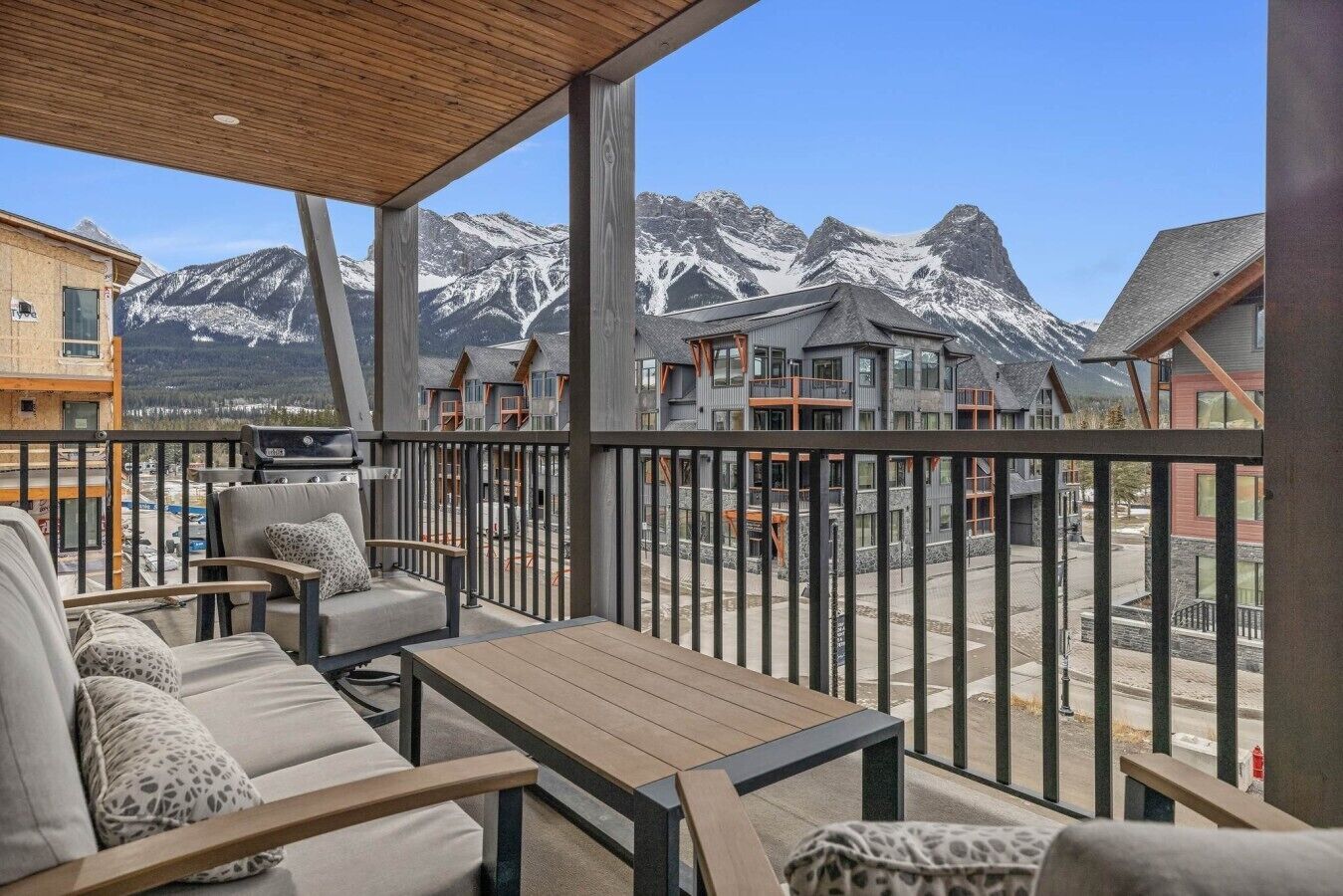 A balcony with outdoor seating and a view of snow-capped mountains.