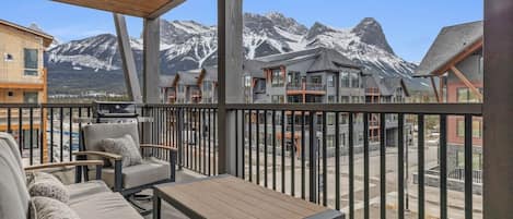 A balcony with outdoor seating and a view of snow-capped mountains.