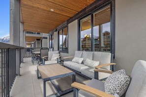 A modern outdoor seating area with a sofa, chairs, and a table, overlooking a mountainous landscape. - Modern 4BR|Hot Tub and Mountain Views|Steps from Downtown (Canmore)