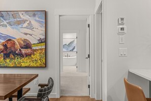 Een modern interieur met een eetgedeelte, een hal naar een badkamer en een thermostaat op de muur.