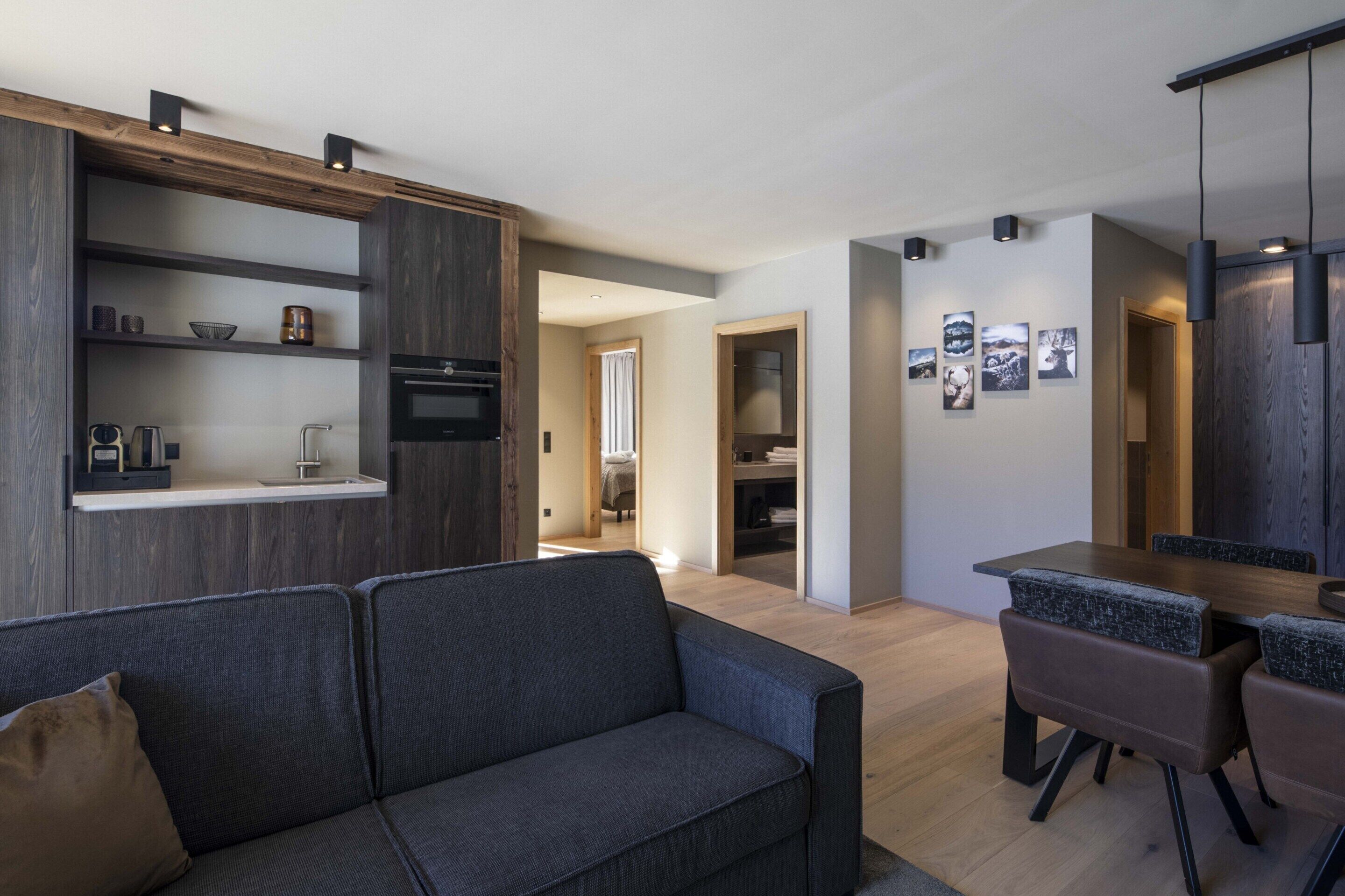 A modern living space with a sofa, dining table, and kitchen area.