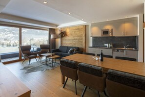 A modern living space with a dining area, sofa, chairs, and a kitchen with a microwave and oven. - Apartment mit 2 Schlafzimmern (Westendorf)