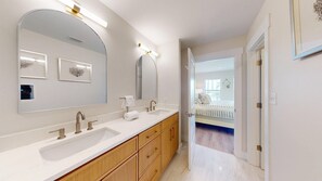 Ein modernes Badezimmer mit zwei Waschbecken, einem großen Spiegel und einer begehbaren Dusche.