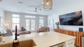 A spacious living area with a large island, a ceiling fan, and a modern chandelier. - Dune Breezin’ | 30A Beach Retreat + 6-Seater Golf Cart (SANTA ROSA BEACH)