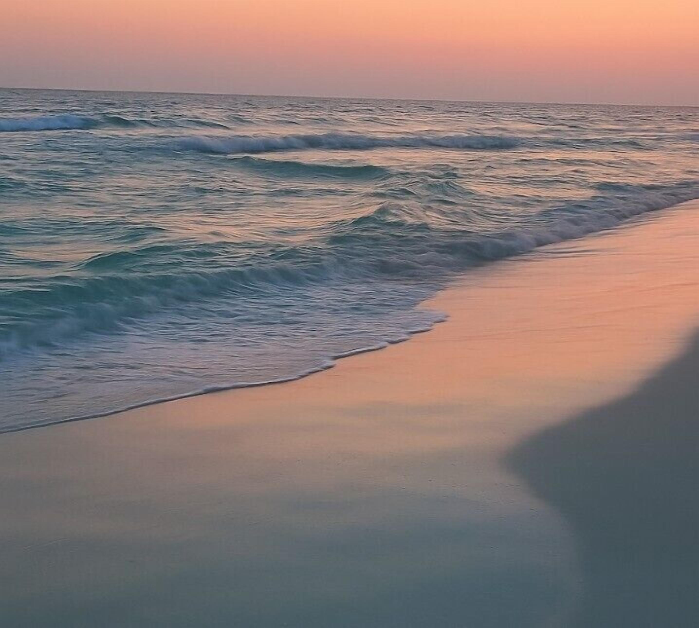 Ein Strand mit an die Küste rollenden Wellen.