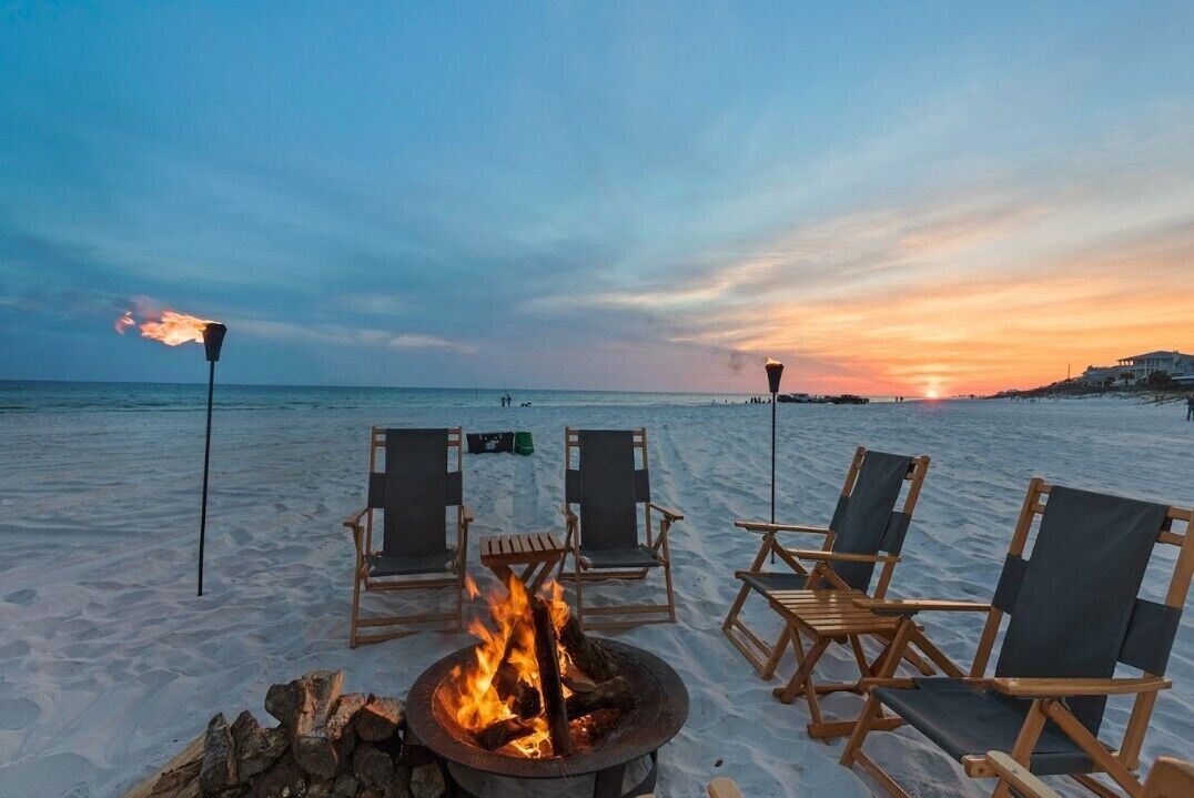 Eine Strandansicht mit Lagerfeuer und Liegestühlen.