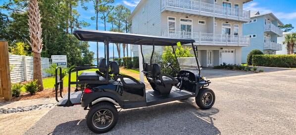Ein Golfmobil steht auf einer Auffahrt, im Hintergrund ist ein mehrstöckiges Gebäude zu sehen.