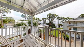 A wooden deck with a railing, overlooking a body of water and a residential area with houses and trees. - Dune Breezin’ | 30A Beach Retreat + 6-Seater Golf Cart (SANTA ROSA BEACH)