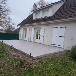 A residential building with a tiled roof, white exterior walls, and a covered driveway.