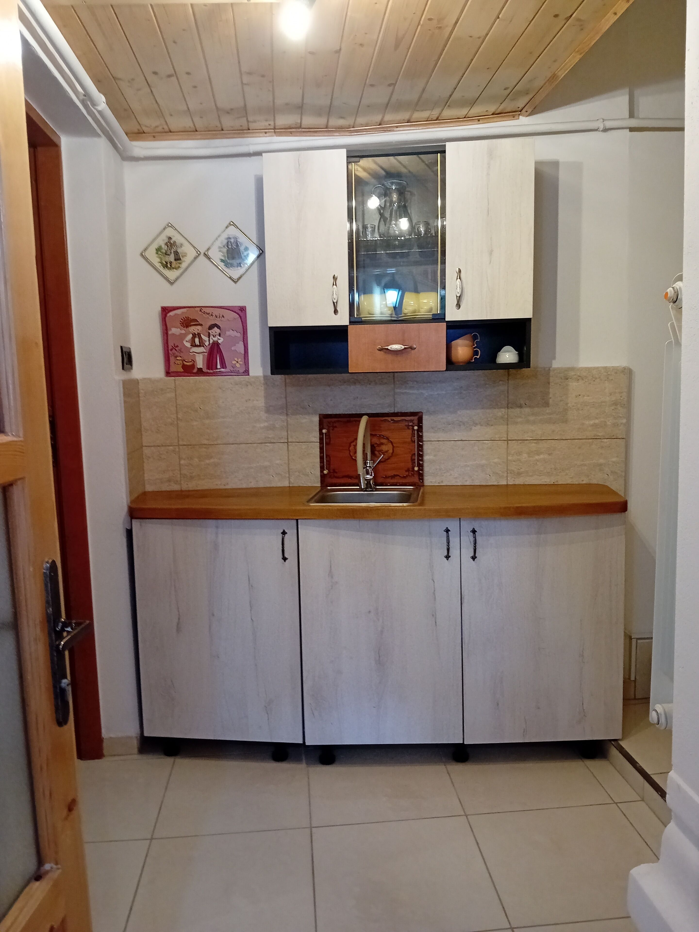 A kitchen with a wooden countertop, white cabinets, a sink, and a backsplash.