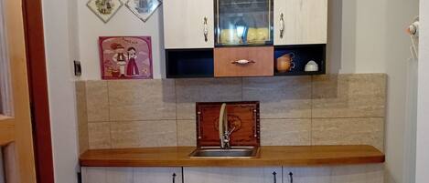 A kitchen with a wooden countertop, white cabinets, a sink, and a backsplash.