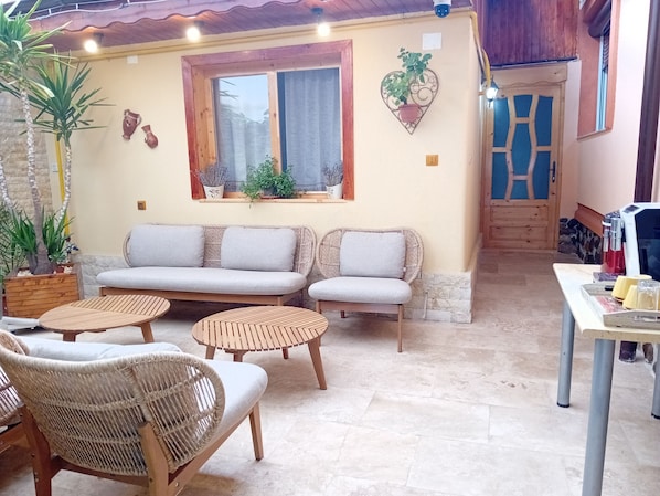 A cozy outdoor seating area with wicker furniture, a cushioned sofa, and a small table.