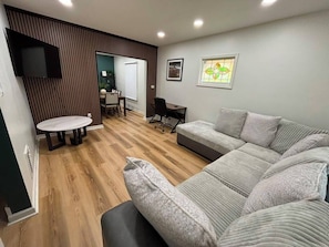 A modern living room with a sofa, a small table, and a TV mounted on the wall.