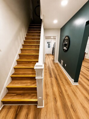 A staircase with wooden steps and white railings leading to a door.
