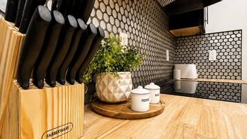 A kitchen with a knife block, a potted plant, and salt and pepper shakers on a wooden countertop.