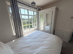 A bedroom with a large bed, a wardrobe, and a window with curtains.
