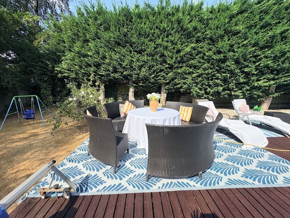 A patio with wicker furniture, a swing set, and a decorative rug.