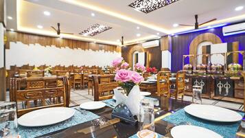 Un restaurante con mobiliario de madera y una mesa central adornada con un jarrón de flores rosas.