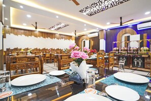 Un restaurante con mobiliario de madera y una mesa central adornada con un jarrón de flores rosas.