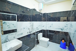 Un baño con lavamanos blanco, inodoro, ducha y espejo.